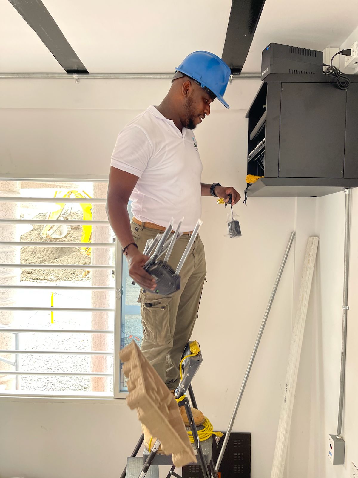 Técnico de JIMP con casco y botas realizando una instalación junto a un gabinete de comunicaciones